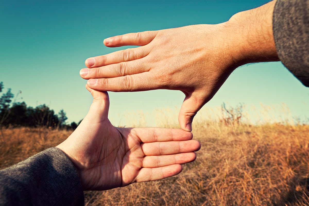 Hands forming a frame over a landscape