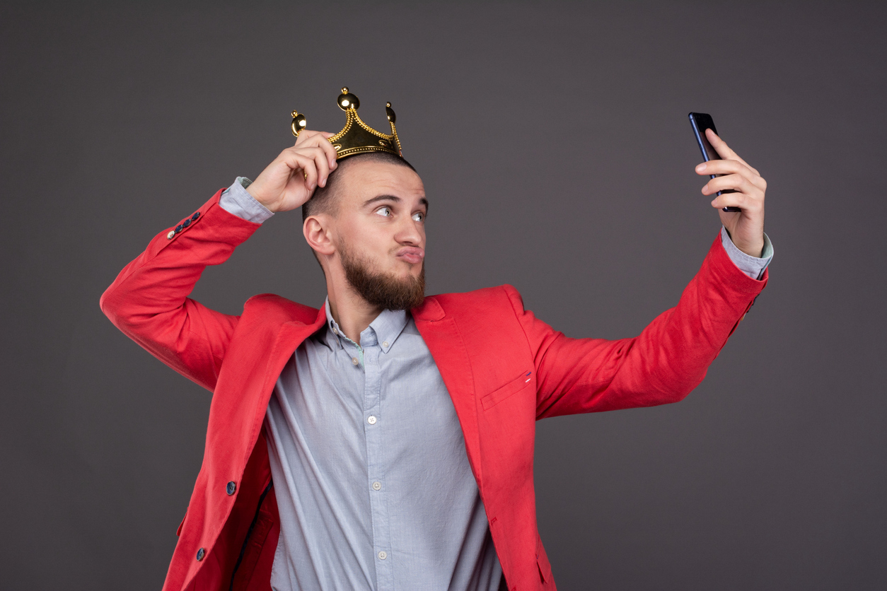 A man wearing a crown and taking a selfie