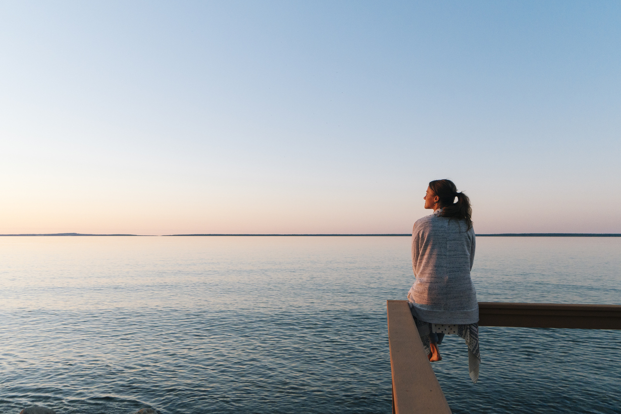 Woman sitting on a ledge overlooking the water peacefully
