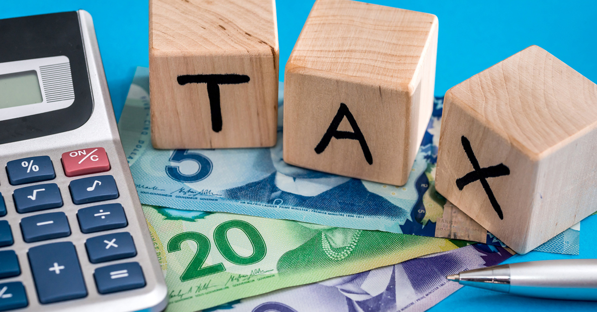 A calculator, Canadian cash bills and the word tax on a table
