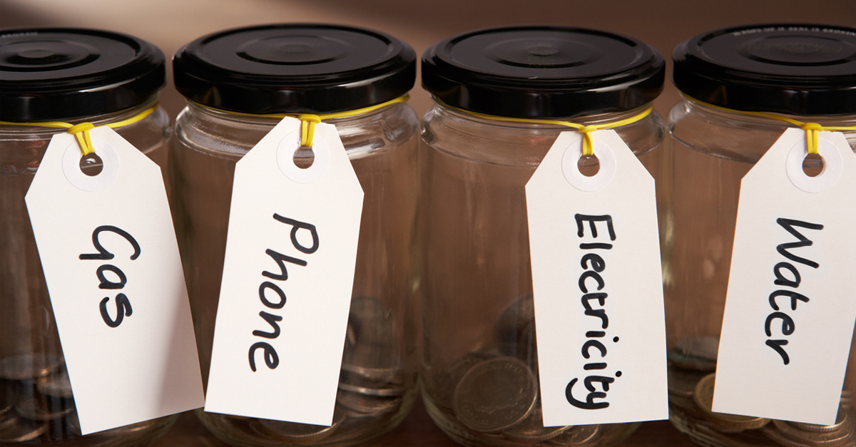 Four jars with coins in them and with different labels like gas, phone, electricity and water